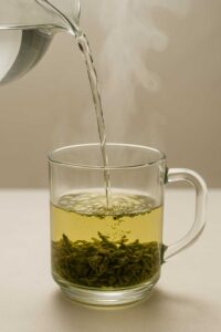 Pouring hot water into a glass mug with tea leaves for brazilian mounjaro recipe