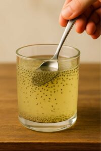 Hand stirring chia seeds into a glass of natural zepbound recipe