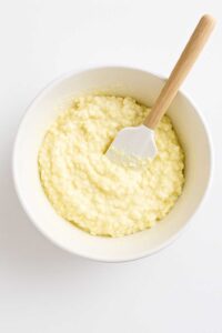 Mixing cottage cheese, egg, and salt in a white bowl with a spatula for cottage cheese bagel recipe​
