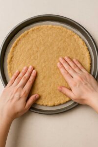 Pressing ground chicken mixture into a thin, even circle on a pizza pan for low-carb ground chicken pizza crust.