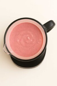 Top view of a blender filled with smooth, blended chocolate covered strawberry protein shake.