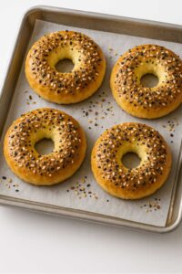 Freshly baked cottage cheese bagels with everything bagel seasoning on a parchment-lined baking sheet