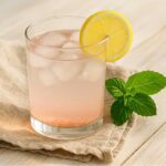 A glass of salt and ice trick recipe​ with lemon slice and mint on a linen napkin.