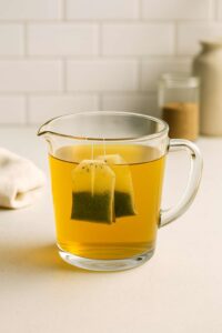 Two green tea bags steeping in hot water for iced peach green tea lemonade.