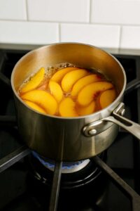 Peach slices simmering on the stove for iced peach green tea lemonade.