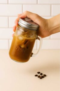 Hand shaking a mason jar of iced brown sugar oatmilk shaken espresso.