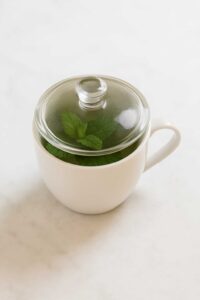Glass-lidded mug steeping lemon balm for weight loss recipe.