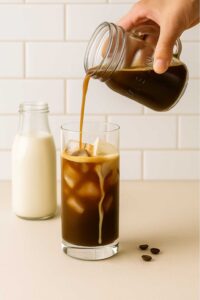 Glass of iced brown sugar oatmilk shaken espresso with oat milk pour.
