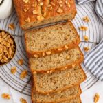 Sliced high protein banana bread with chopped walnuts on a cooling rack.
