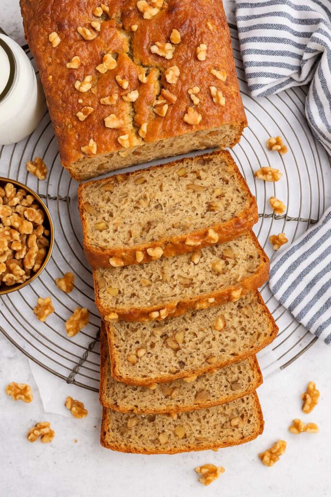 Sliced high protein banana bread with chopped walnuts on a cooling rack.