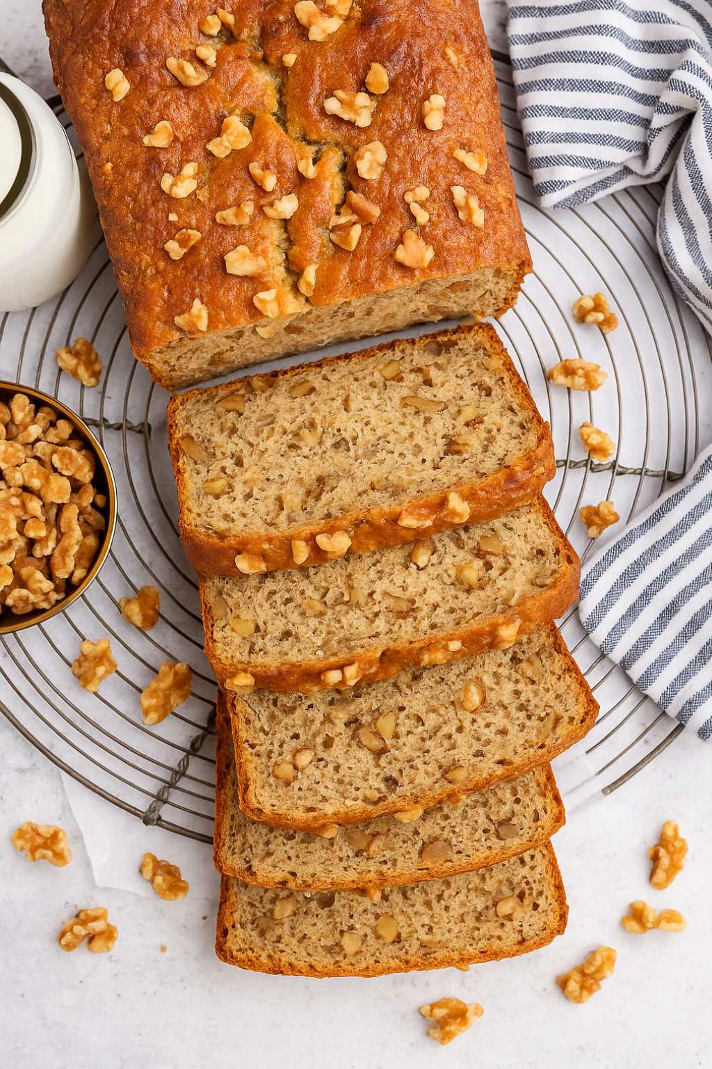Sliced high protein banana bread with chopped walnuts on a cooling rack.